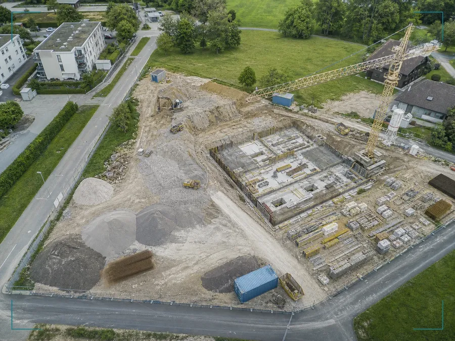 Schräges Drohnen-Luftbild einer Schweizer Baustelle mit Erdarbeiten